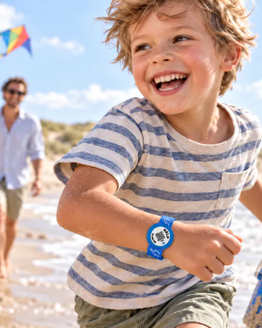 Een lachende jongen rent over het strand met een blauwe ICESCAN-armband om zijn pols.